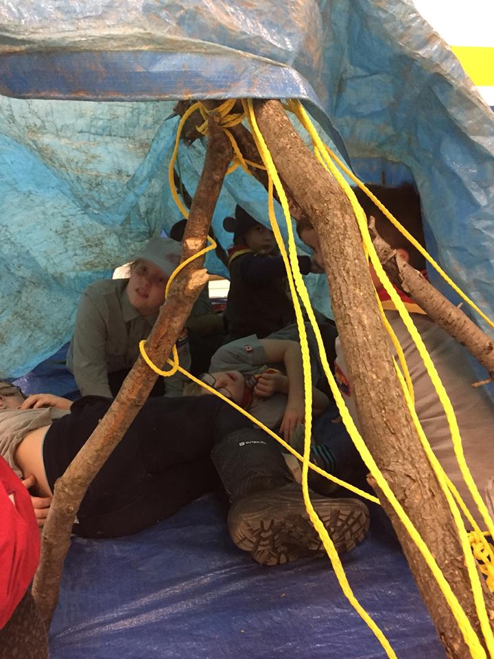 Scouts testing a shelter built with tarps and poles